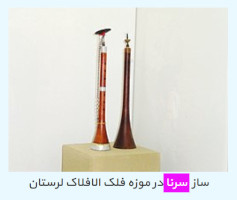 Two sornas standing upright on a pedestal. The caption, in Persian, means "sorna instruments at Lorestan Falak Museum"